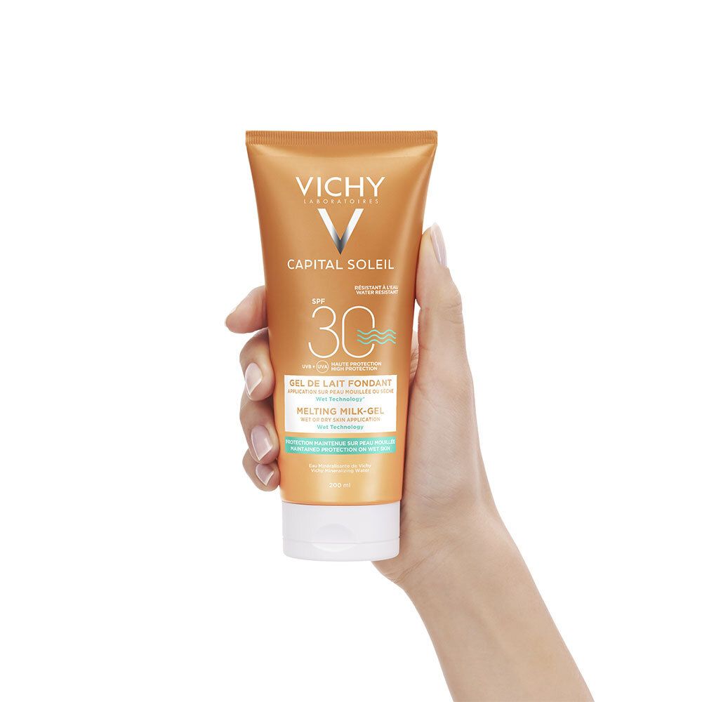 Main tenant le tube. Inscriptions: VICHY, CAPITAL SOLEIL, SPF 30. Texte: Gel de Lait Fondant, Melting Milk-Gel.