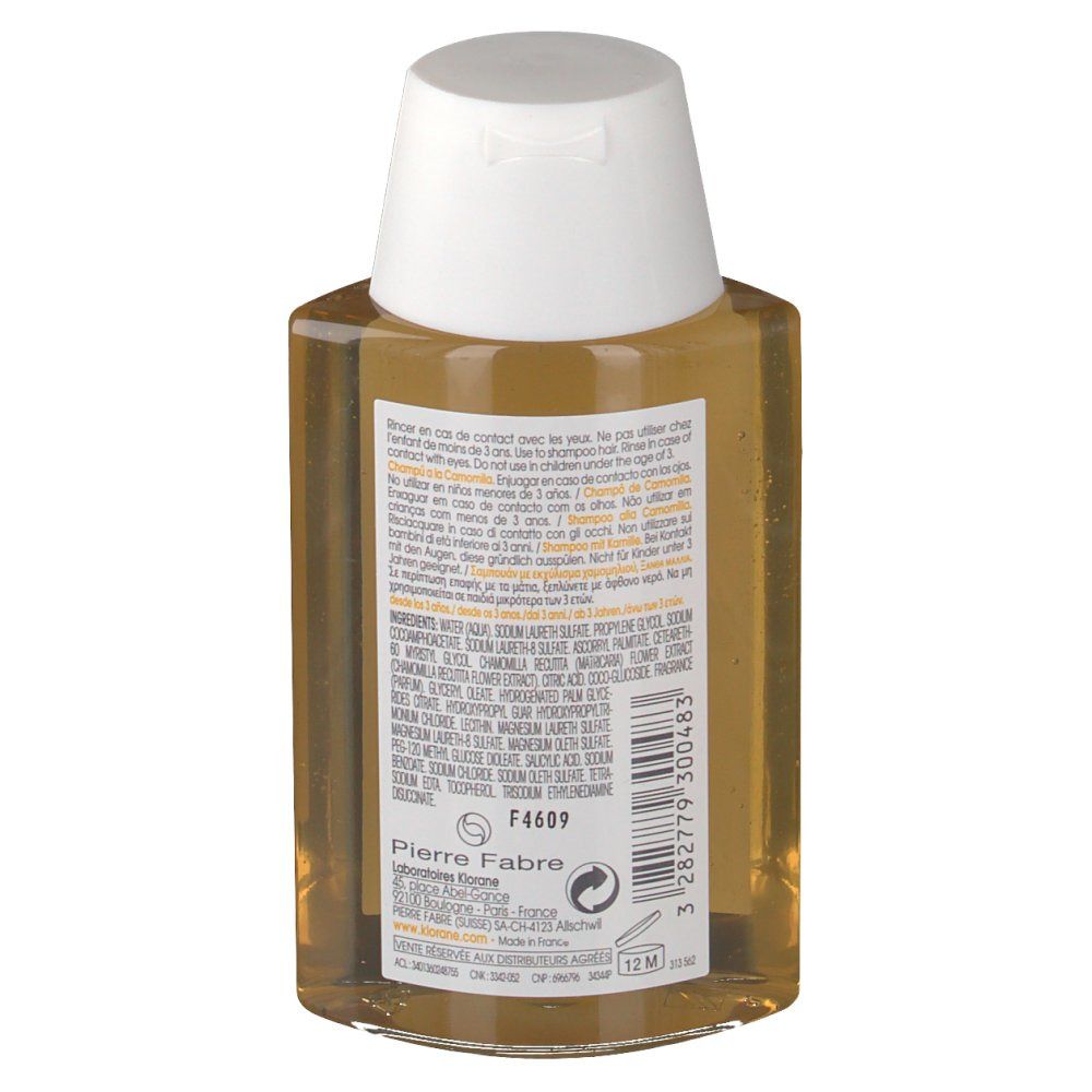Achterkant van de Klorane Shampooing À La Camomille fles. Transparante vloeistof. Tekst met ingrediënten en waarschuwingen. Pierre Fabre logo.