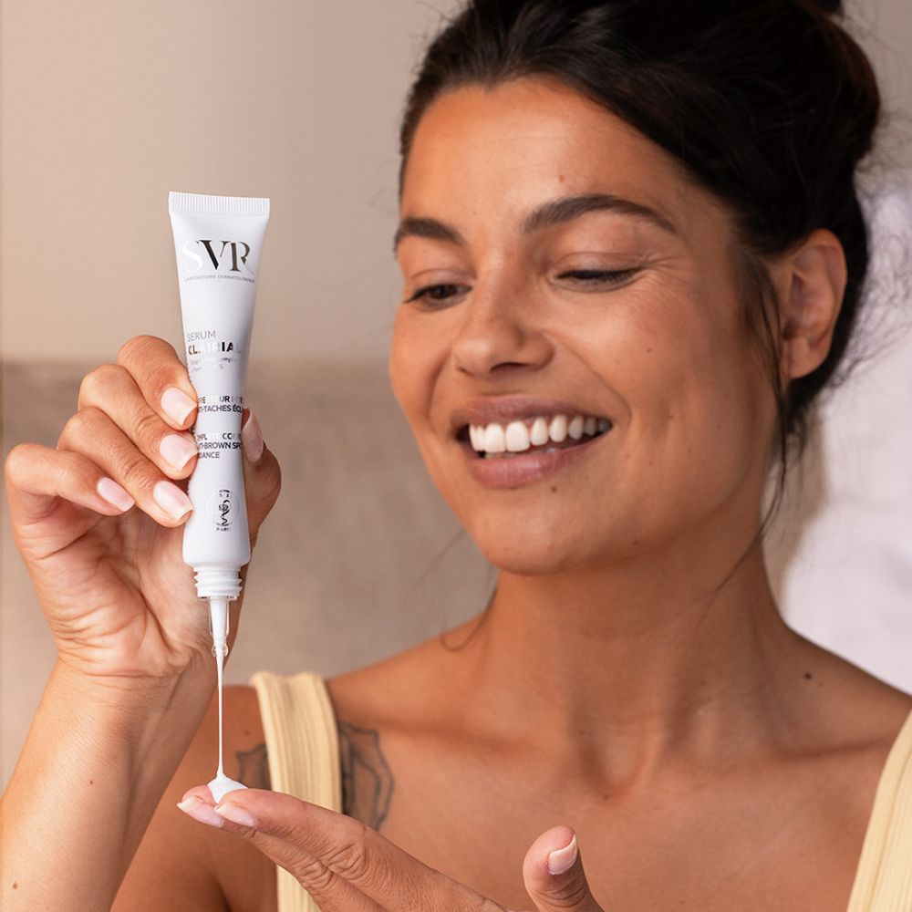 Femme tenant un tube de sérum. Le sérum est appliqué sur la main. Inscriptions: SVR, Clairial Serum.