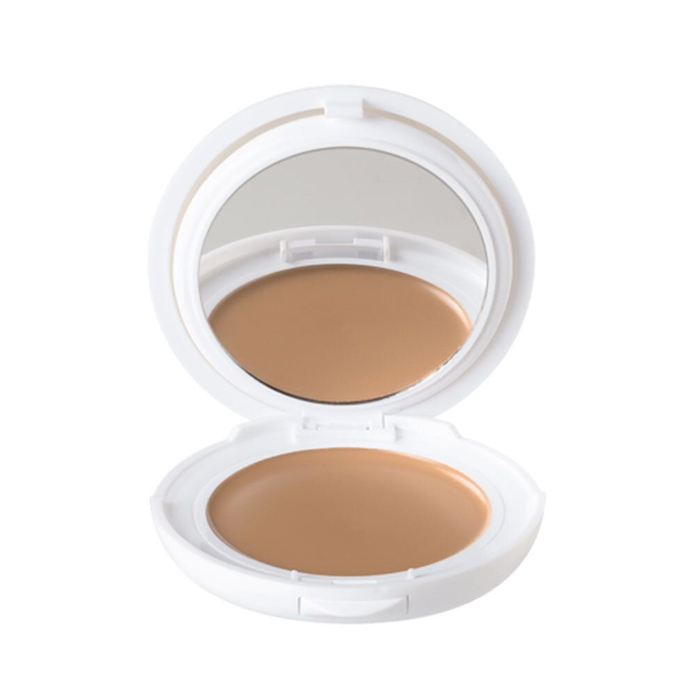 Witte compactpoeder met spiegel en getint product. Open, rond, met bruine crème.