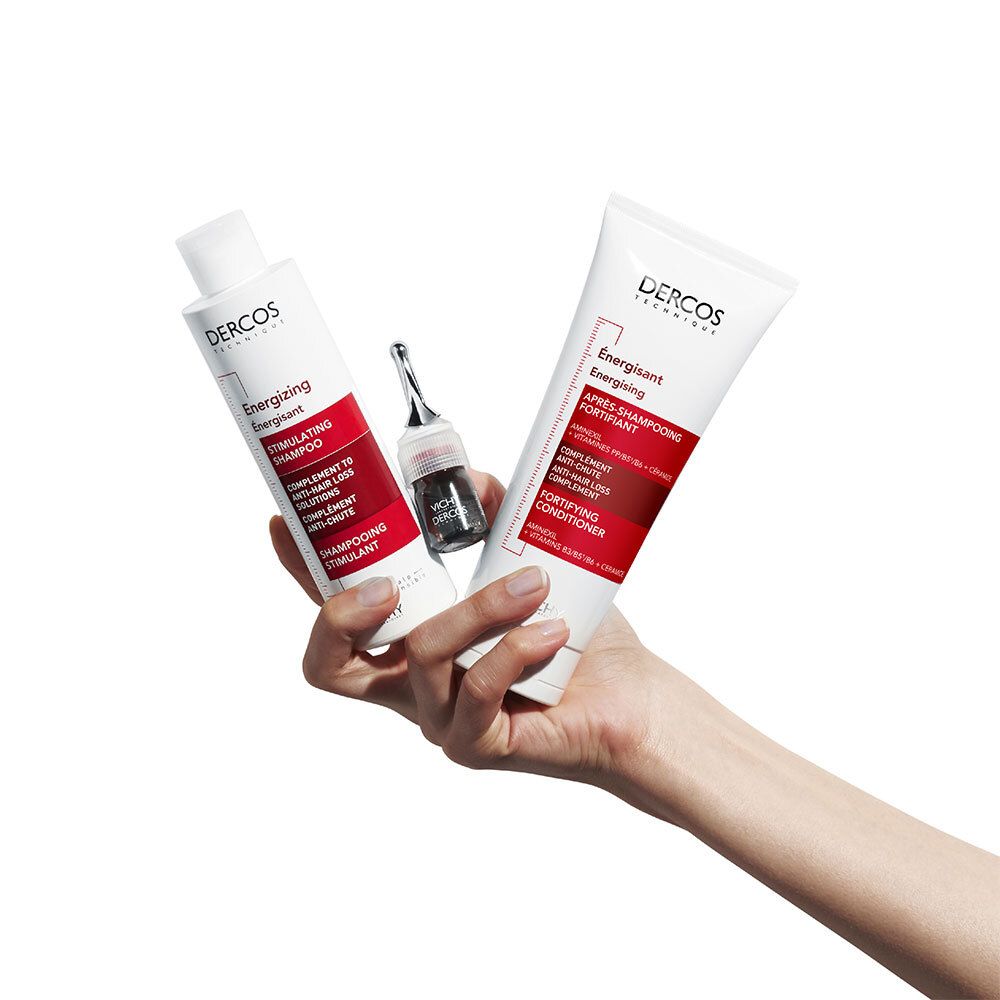 Drie producten in de hand: shampoo, conditioner en een ampul. Opschrift: Dercos Energising.