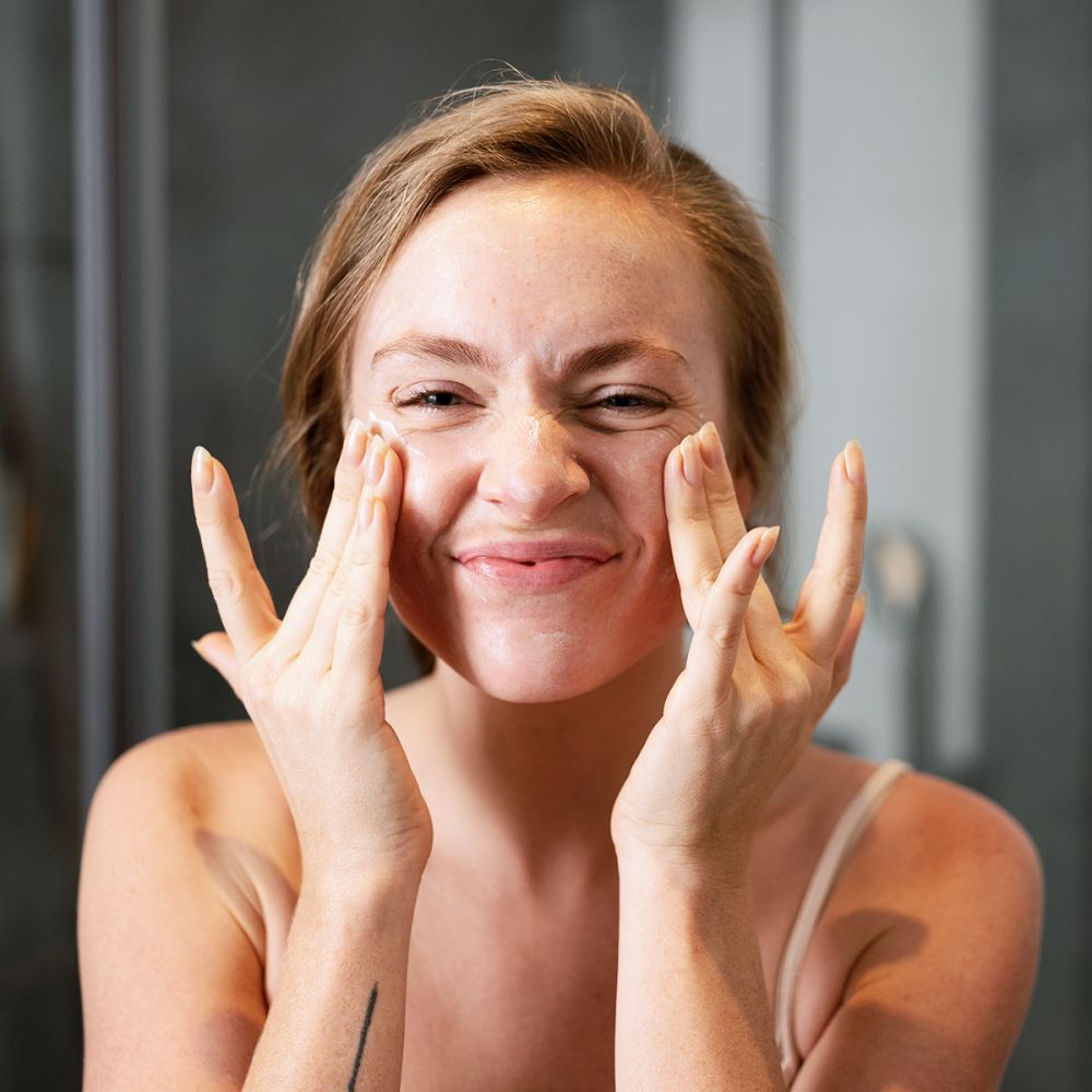 Femme appliquant de la crème. Visage, mains. Arrière-plan salle de bain.