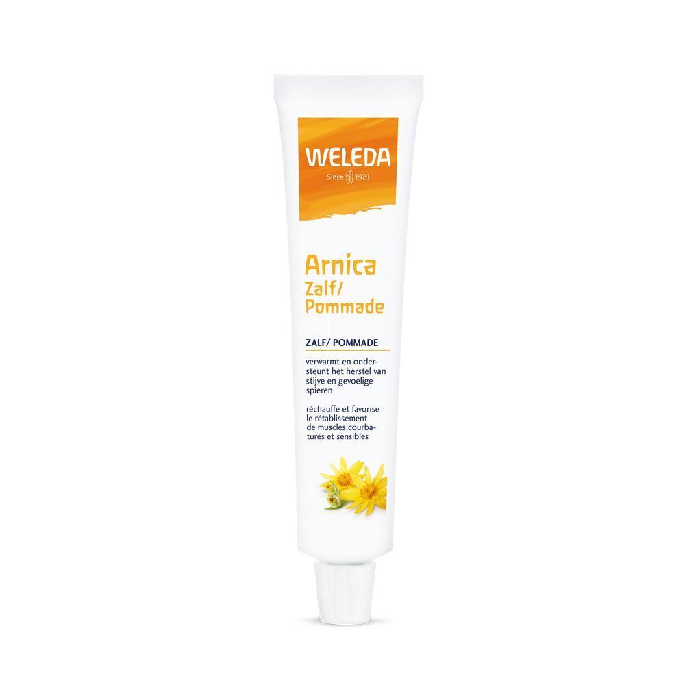 Weleda Arnica Zalf/Pommade tube. Wit, met geel-oranje logo en productnaam. Bevat bloemenillustratie.