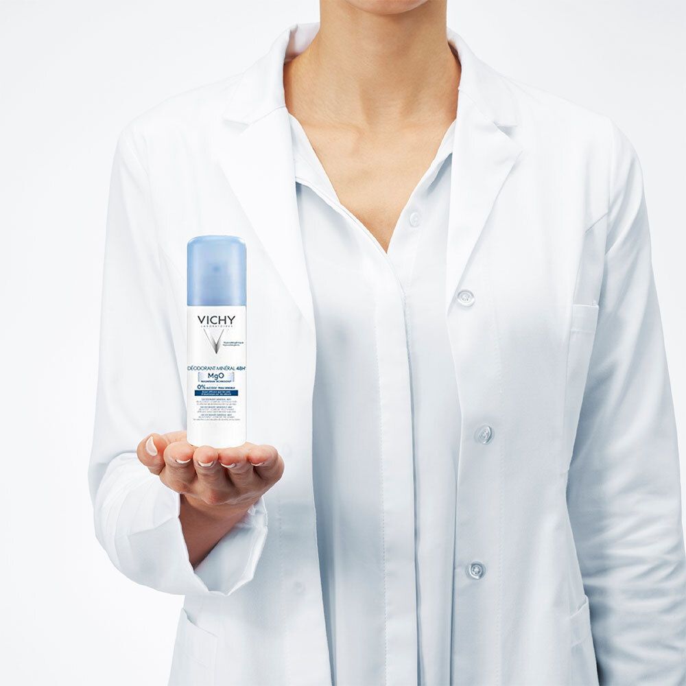 Persoon houdt Vichy deodorant vast. Witte fles met blauwe dop. Opschrift: Mineral Deodorant 48H, MgO, 0% alcohol.