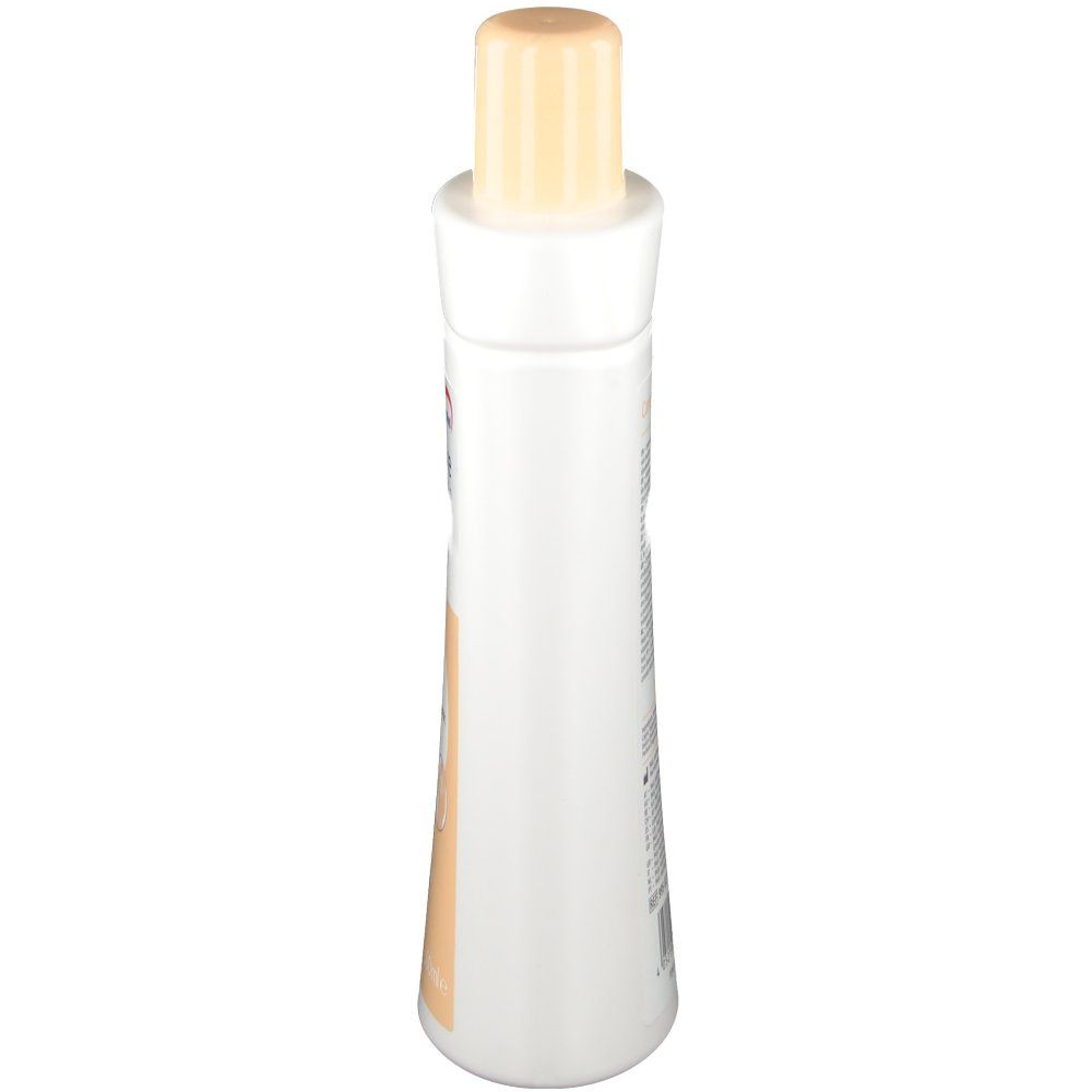 Die Flasche ist weiß mit einem beigen Verschluss. Die Form ist länglich und leicht tailliert. Die Flasche ist von oben fotografiert.