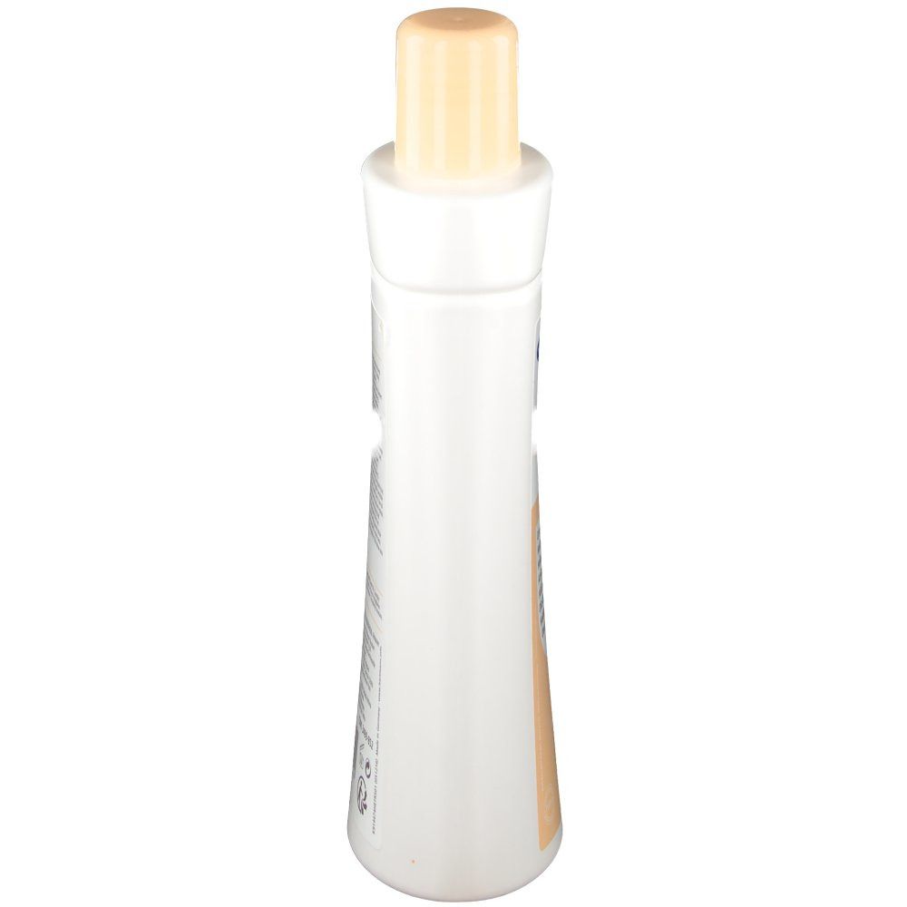 Die Flasche ist weiß mit einem beigen Verschluss. Die Form ist länglich und leicht tailliert. Die Flasche ist von oben fotografiert.