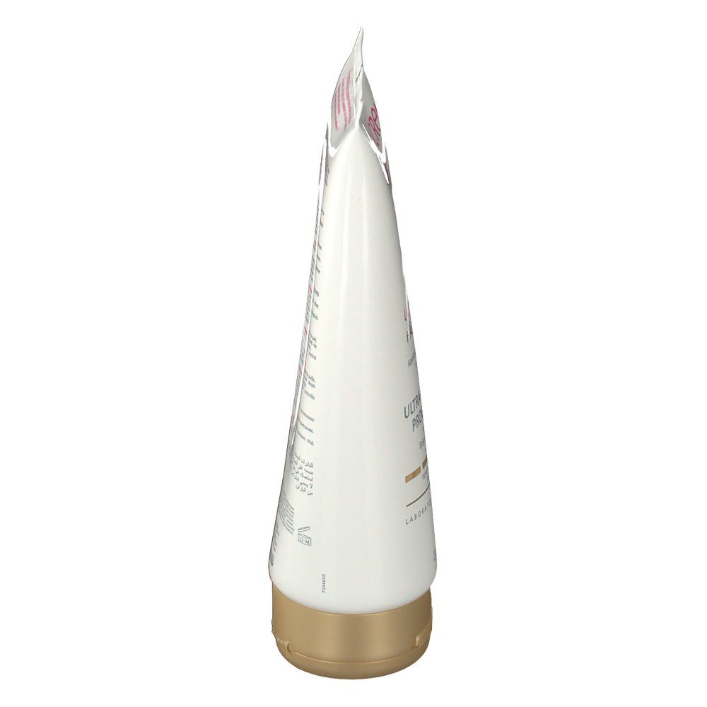 Zijaanzicht van een tube met gouden dop. Wit met roze en gouden accenten. Tekst.