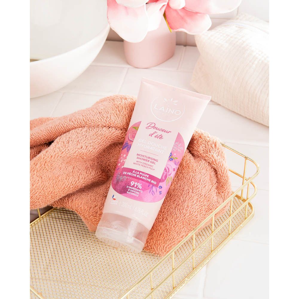Tube rose dans panier doré avec serviette. Logo LAINO et 'Douceur d'été' visibles. Gel douche hydratant.