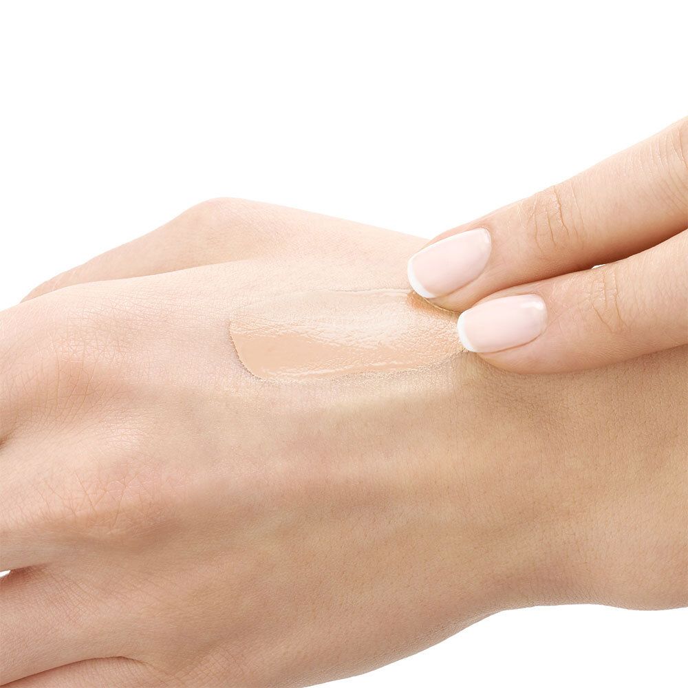 Hand met aangebrachte beige crème. Huidskleur zichtbaar.