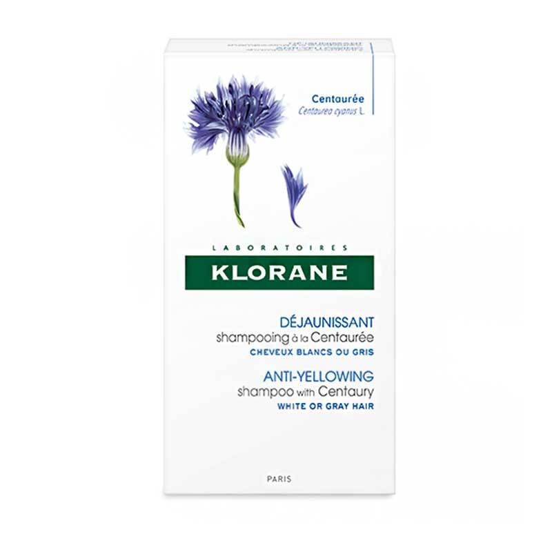 Emballage blanc avec logo fleur bleue. Texte: Klorane, Déjaunissant, shampooing à la Centaurée, cheveux blancs ou gris.