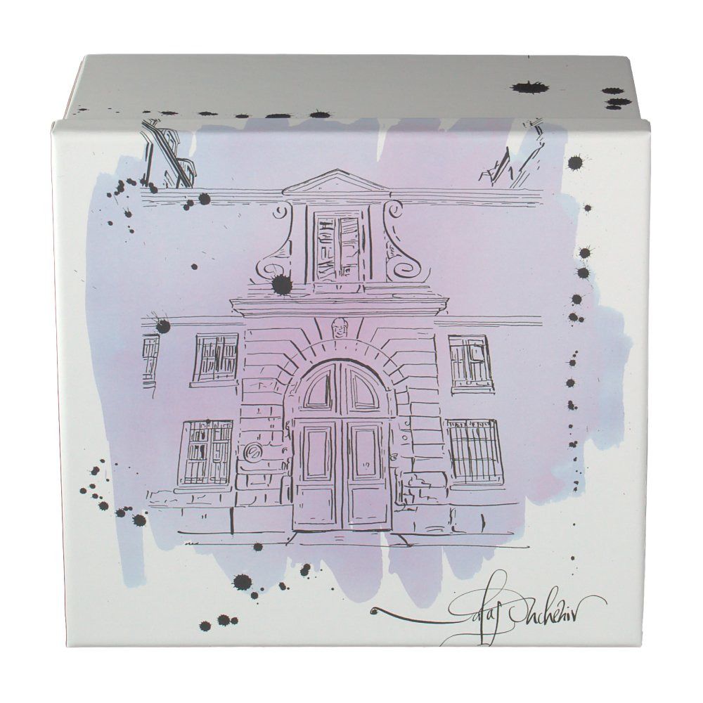 Boîte blanche avec illustration d'un bâtiment. Signature Nicolas Ouchenir. Taches d'encre noire.
