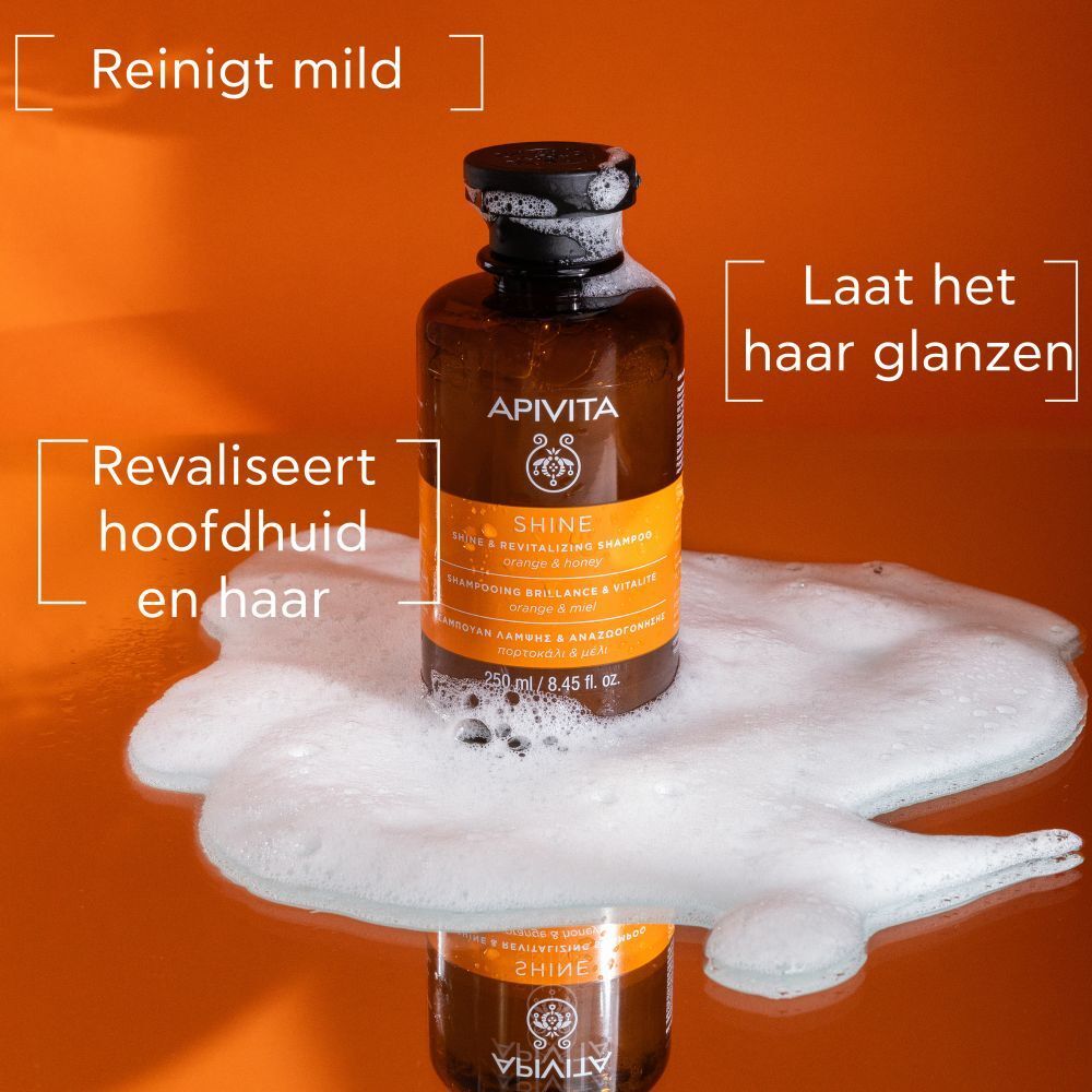 Shampoo fles met schuim. Tekst: APIVITA SHINE. Sinaasappel & honing. Reinigt mild, revitaliseert.
