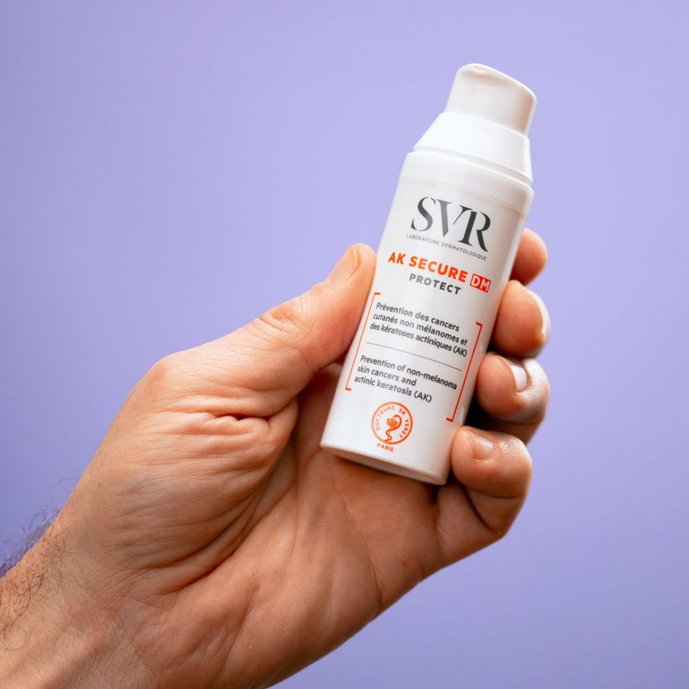 Produit tenu en main. Flacon blanc avec logo SVR et texte. Nom du produit : AK SECURE DM PROTECT.