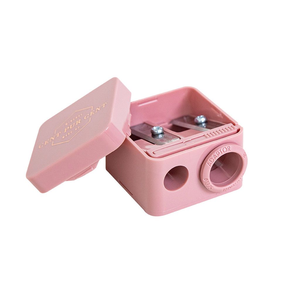 Taille-crayon rose à deux ouvertures. Inscription: Mineral Cent Pur Cent Make Up. Couvercle ouvert, lames visibles.