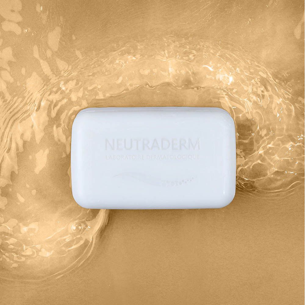 Witte Neutraderm zeep in goudkleurig water. Rechthoekige vorm. Logo zichtbaar.
