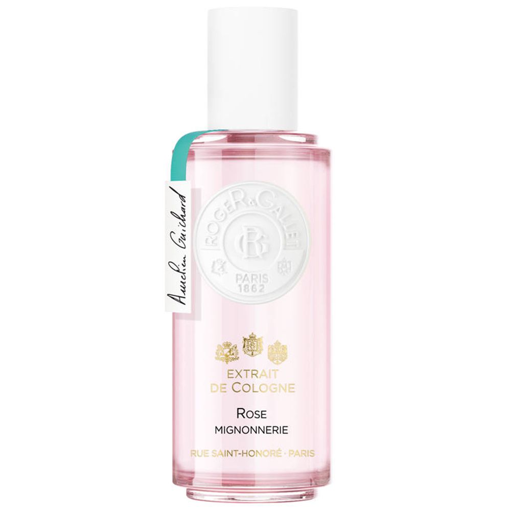 Flacon de parfum rose avec bouchon blanc et étiquette. Inscription : EXTRAIT DE COLOGNE Rose Mignonnerie. Étiquette verte avec nom.