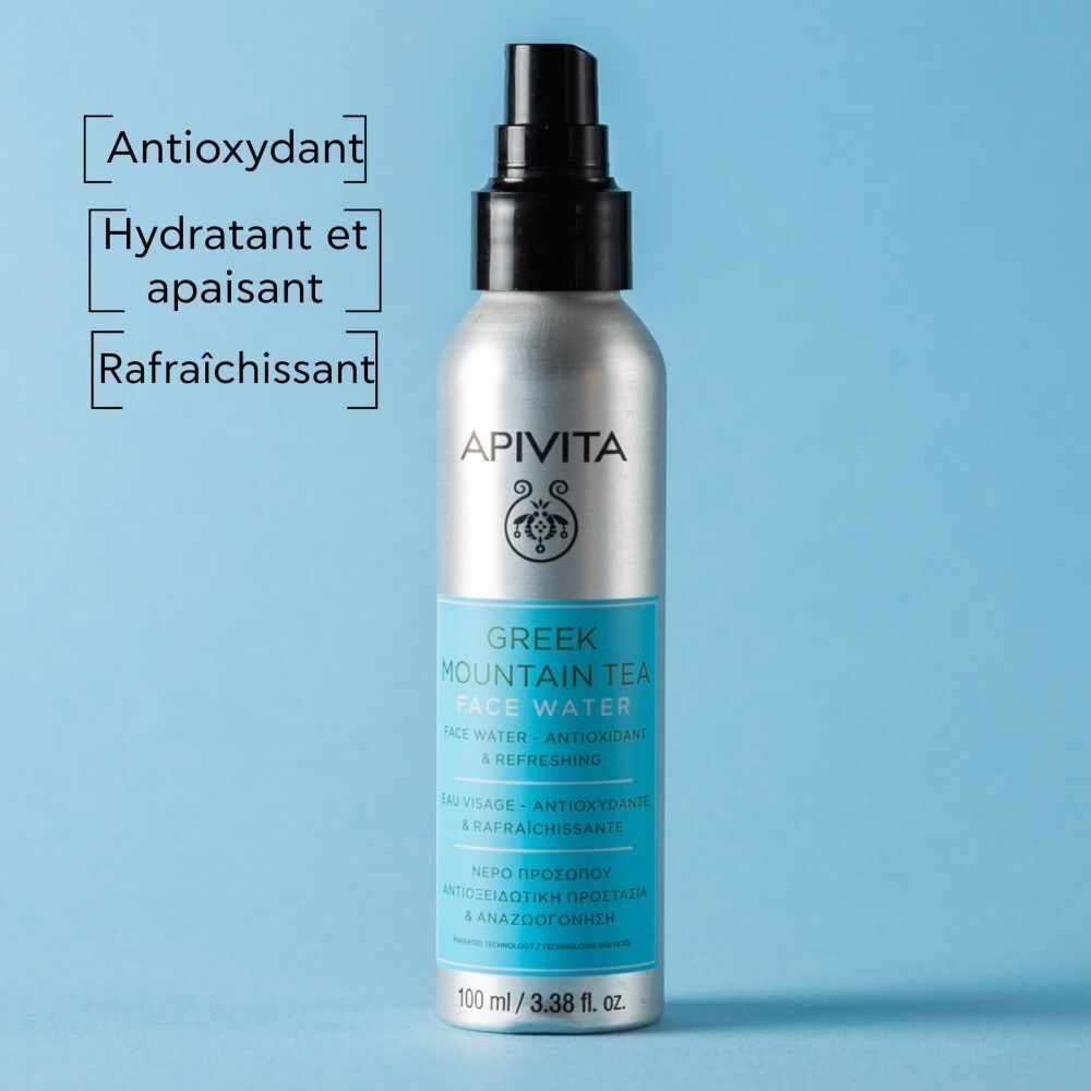 Flacon spray argenté, bouchon noir. Étiquettes bleues avec texte. Marque APIVITA.