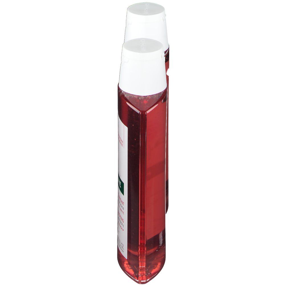 Deux flacons de shampooing, vue latérale. Bouchons blancs, flacons transparents avec liquide rouge. Nom du produit: KLORANE Shampooing à la pivoine.
