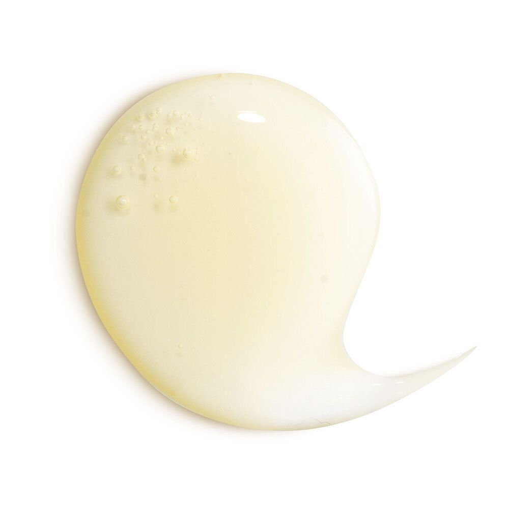 Close-up van een gele shampoo substantie die over een wit oppervlak loopt.