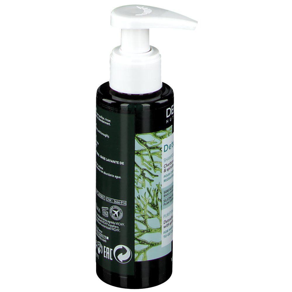 Flacon foncé avec pompe blanche. Étiquette avec texte et plantes vertes. Nom du produit. Vue latérale.