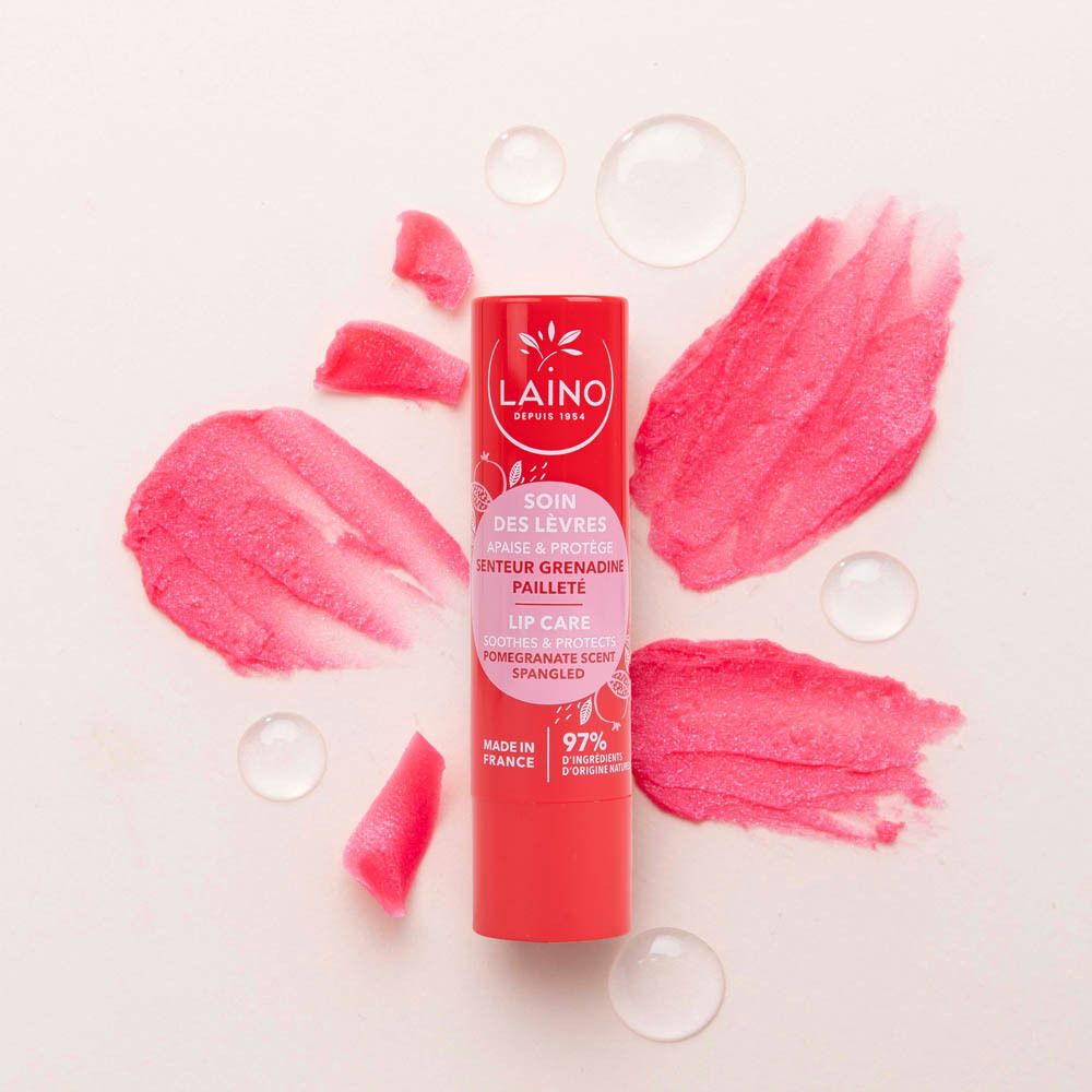 Stick de soin des lèvres rouge avec éclaboussures roses et gouttes d'eau. Produit et texte visibles.
