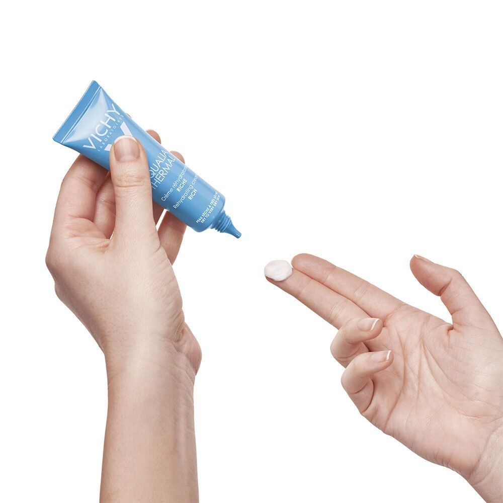 Handen houden tube en crème vast. Crème wordt op de vinger aangebracht.