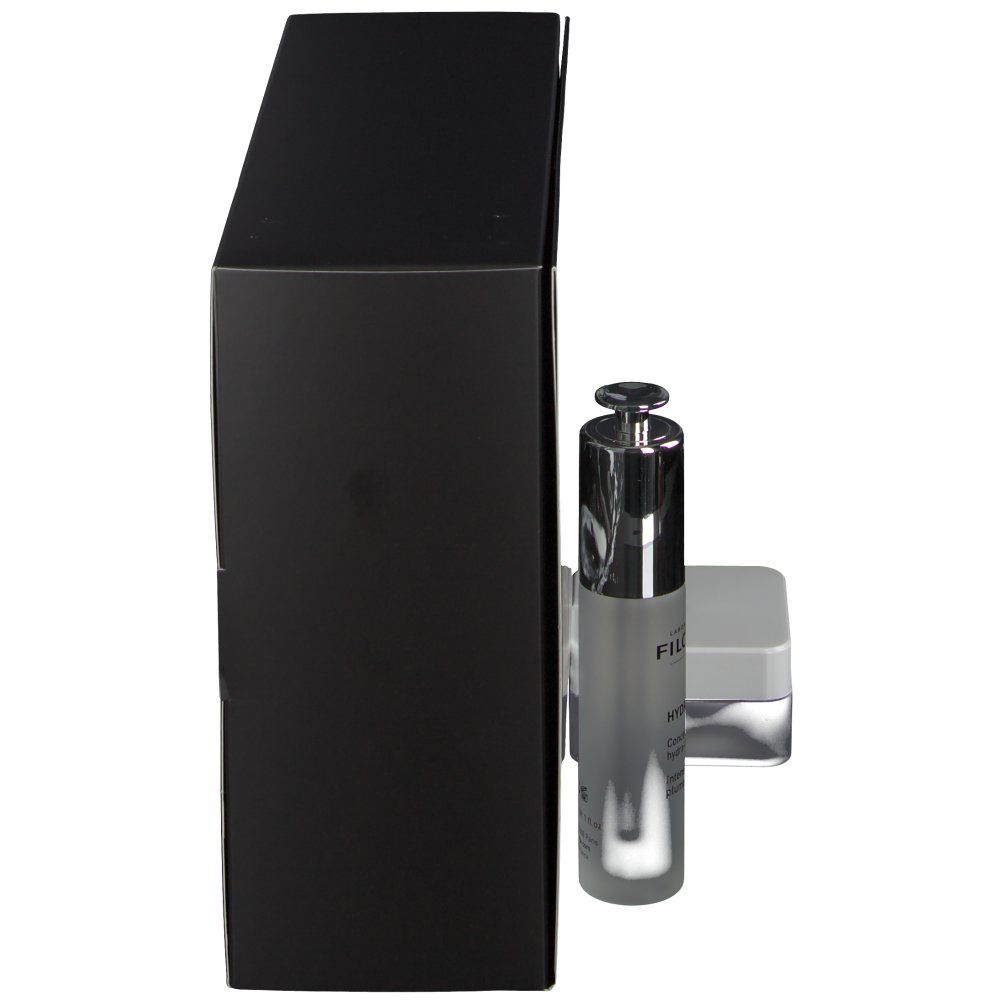 Schwarze Geschenkbox mit Filorga-Produkten. Enthält eine Flasche und einen Tiegel. Seitenansicht. Flasche mit Sprühkopf.