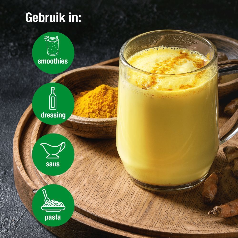 Kurkuma drank in glas, poeder en gember op dienblad. Gebruikt in smoothies, dressing, saus en pasta.