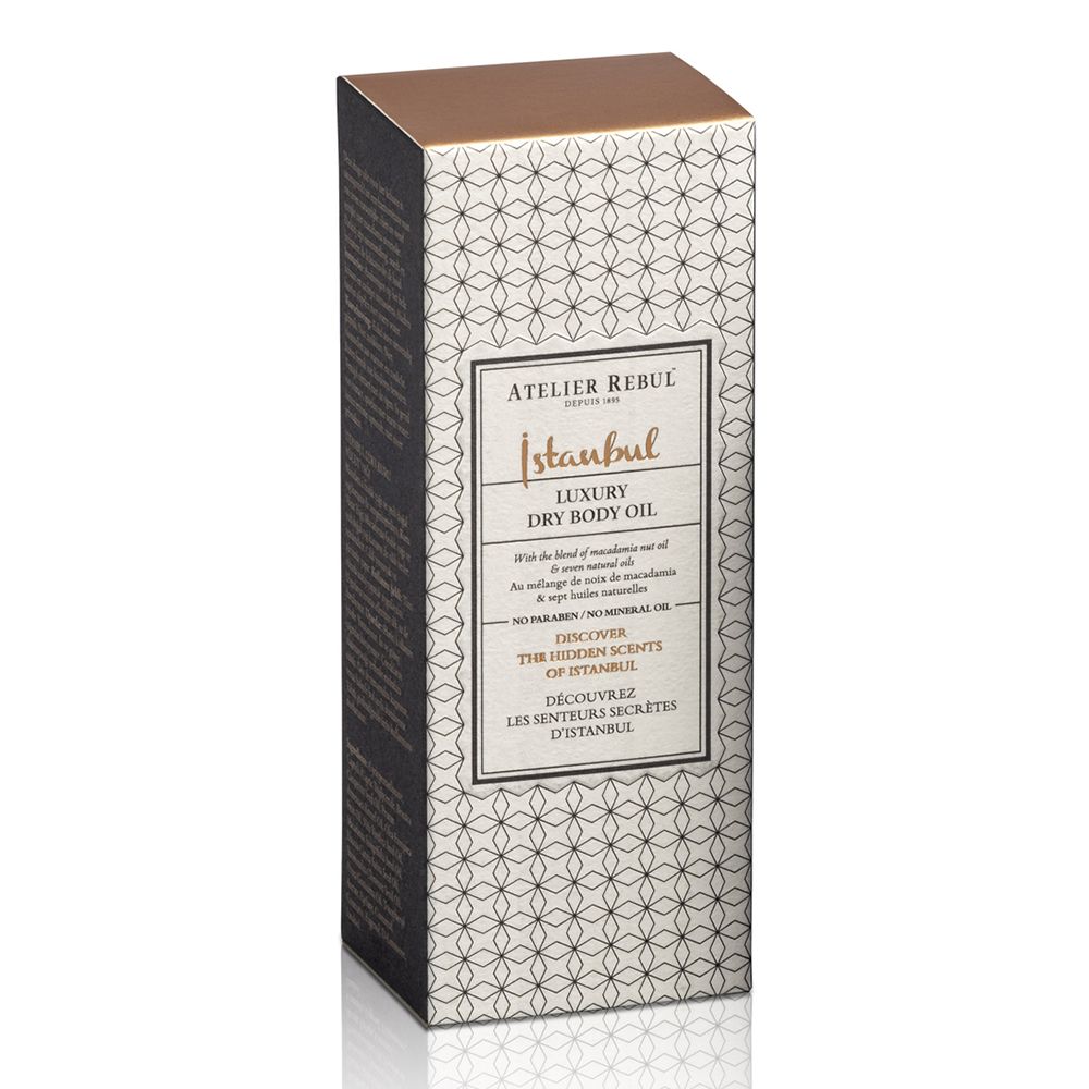 Hoge, rechthoekige doos met productinformatie. Opschrift: ATELIER REBUL Istanbul Luxury Dry Body Oil.