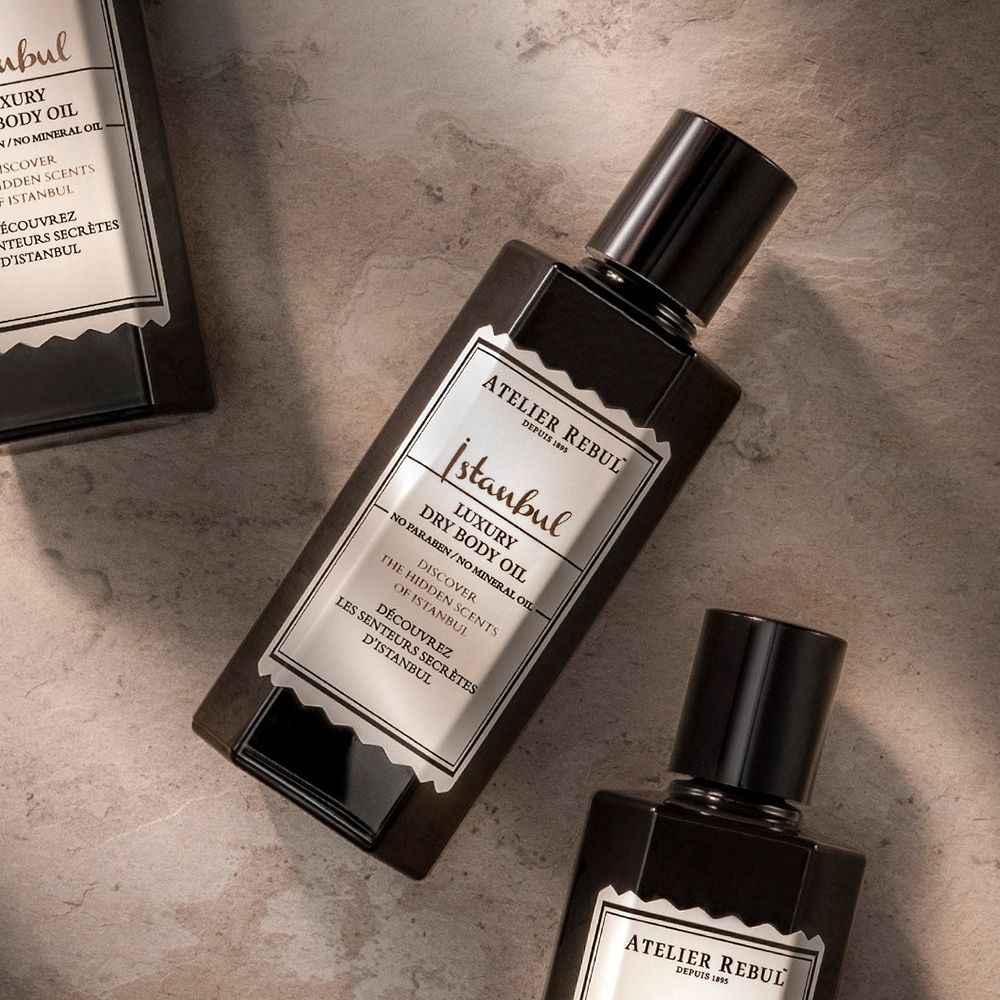 Drie zwarte flessen met zwarte dop. Opschrift: ATELIER REBUL Istanbul Luxury Dry Body Oil.