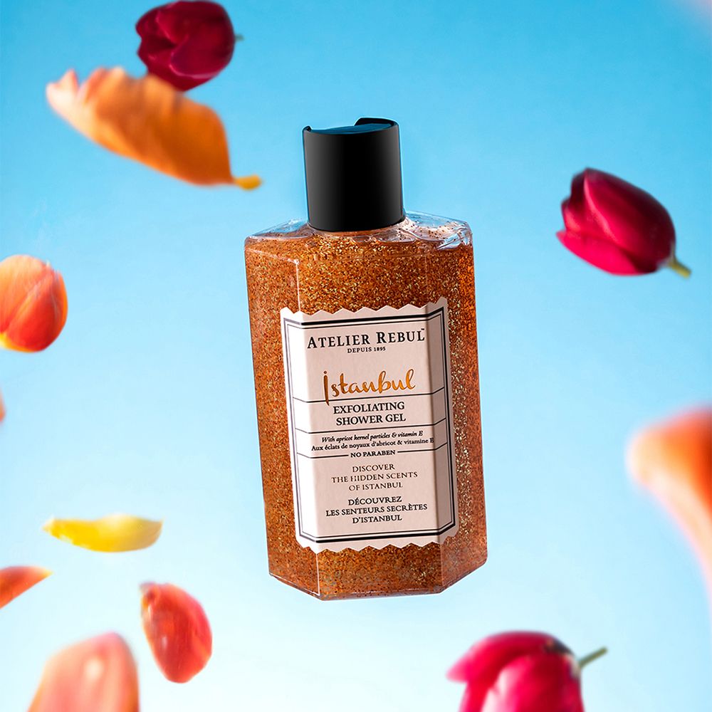 Exfoliërende douchegel. Fles met zwarte dop, omringd door bloemen. Label met productnaam en merk.
