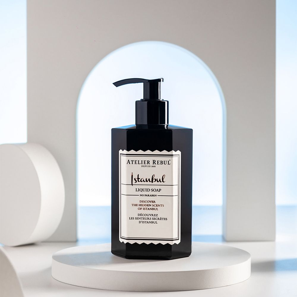 Zwarte vloeibare zeep met pomp op wit voetstuk. Opschrift: ATELIER REBUL Istanbul Liquid Soap.