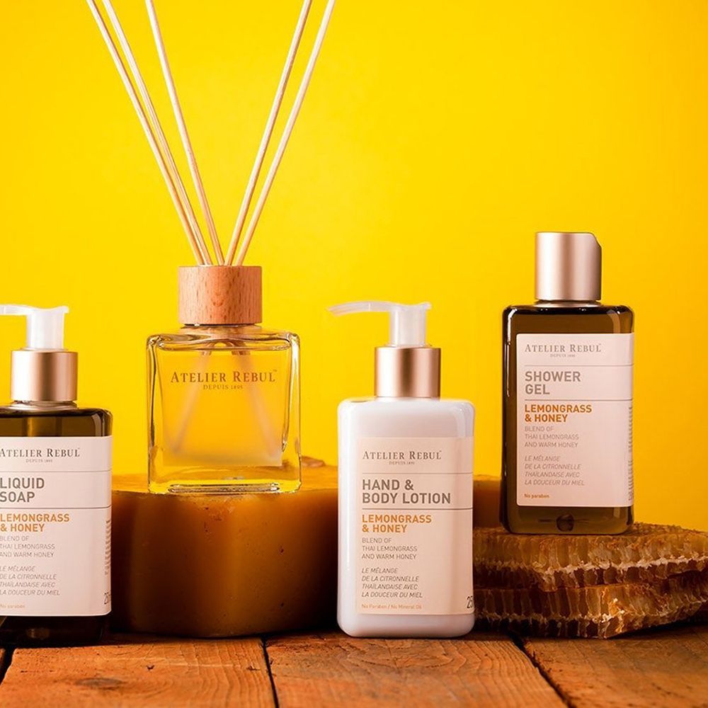 Productreeks met hand- en bodylotion, vloeibare zeep, douchegel en geurverspreider. Op gele achtergrond, op hout en honingraat geplaatst.