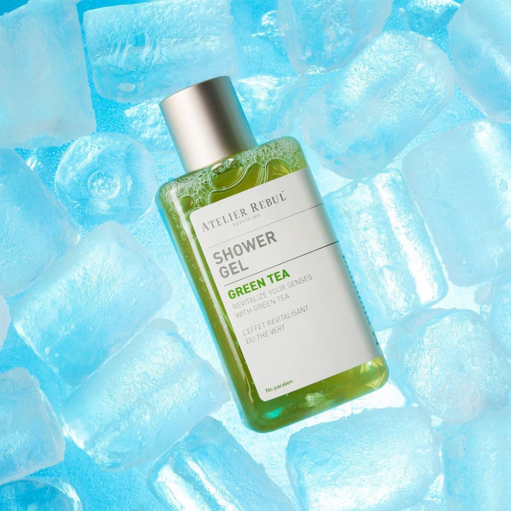 Gel douche vert dans des glaçons. Flacon rectangulaire avec bouchon doré et étiquette.