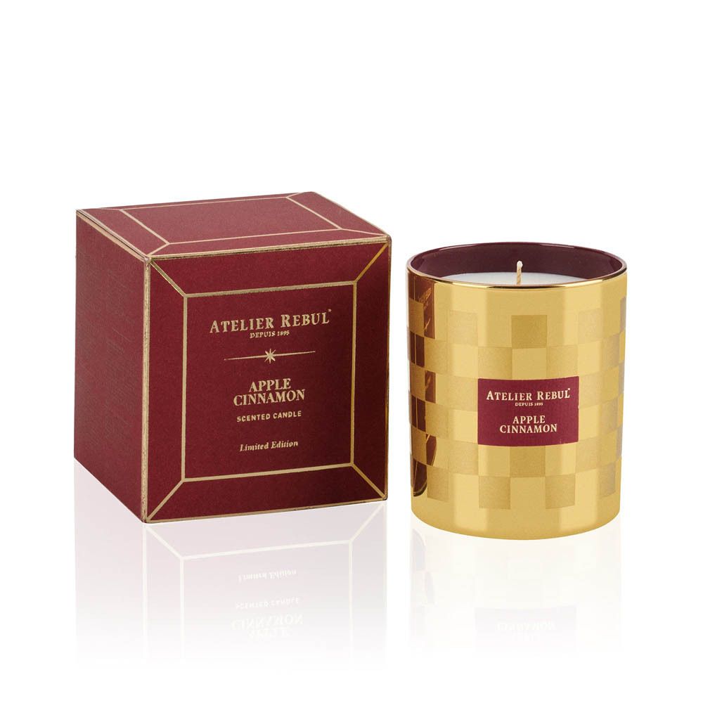 Bougie dorée à motif damier. Étiquette "ATELIER REBUL", "APPLE CINNAMON". Boîte rouge.