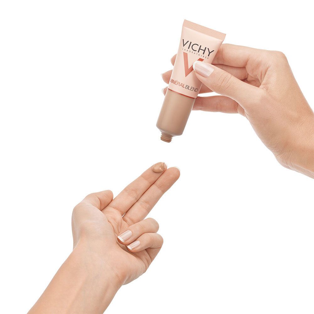 Main pressant du VICHY Minéralblend Make-up Fluid 11 granite sur un doigt. Produit visible.