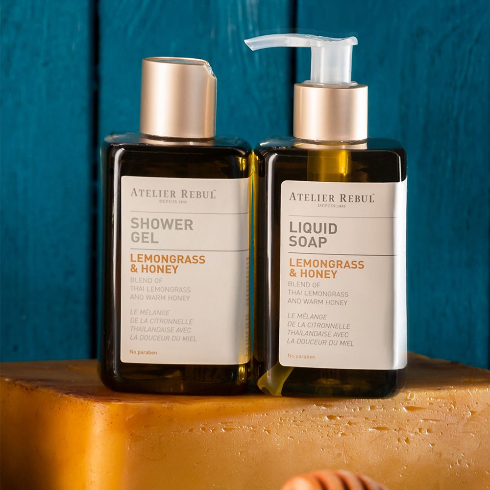 Twee flessen: Shower Gel en Liquid Soap. Opschrift: Lemongrass & Honey. Gouden doppen.