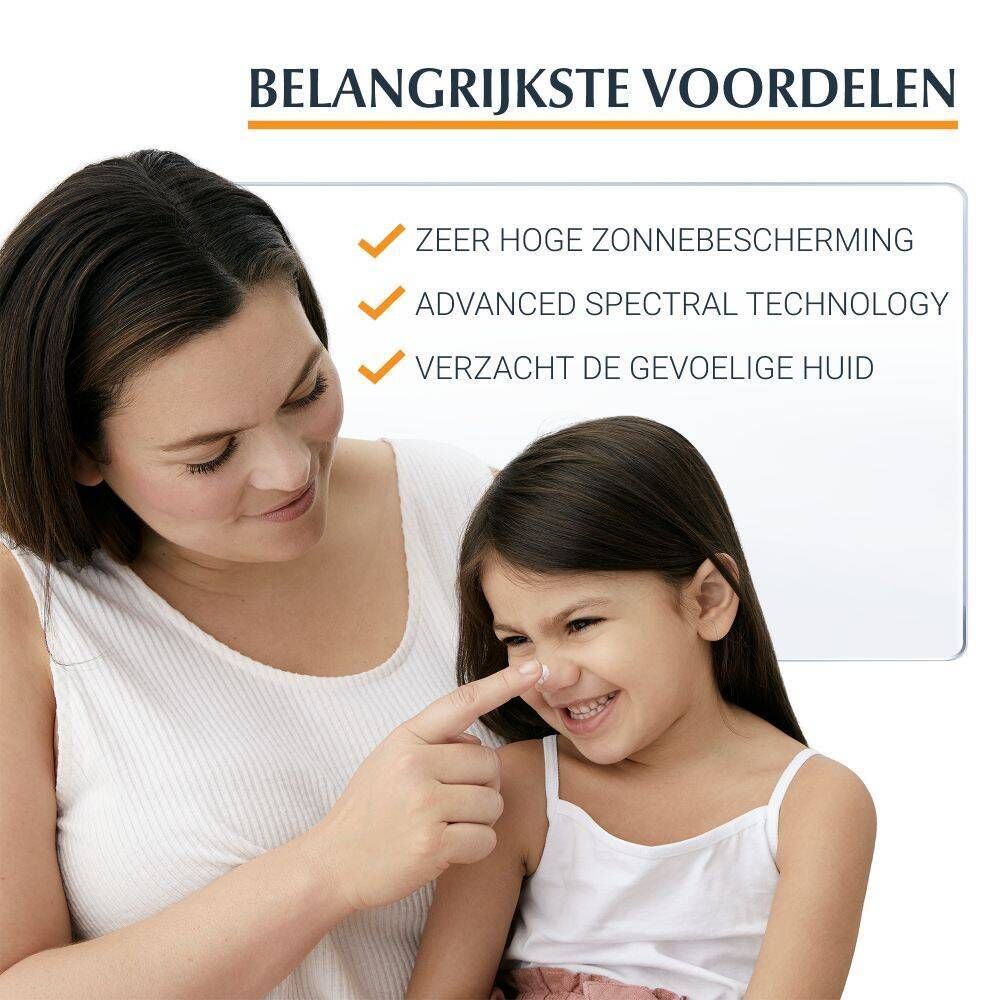 Moeder en kind. De moeder brengt zonnecrème aan op de neus van het kind. Tekst: Voordelen: Zeer hoge bescherming tegen de zon.