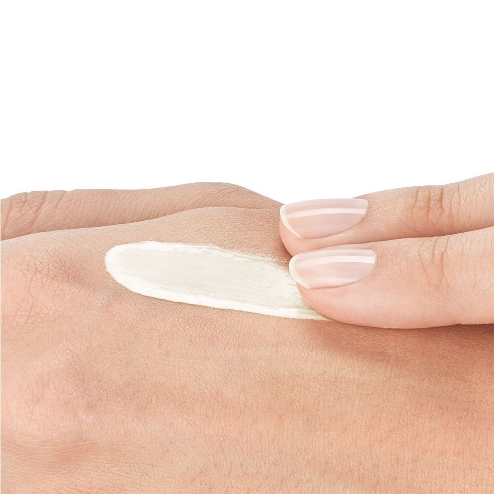 Crème sur la peau. Crème blanche sur la main. Nom du produit non visible.