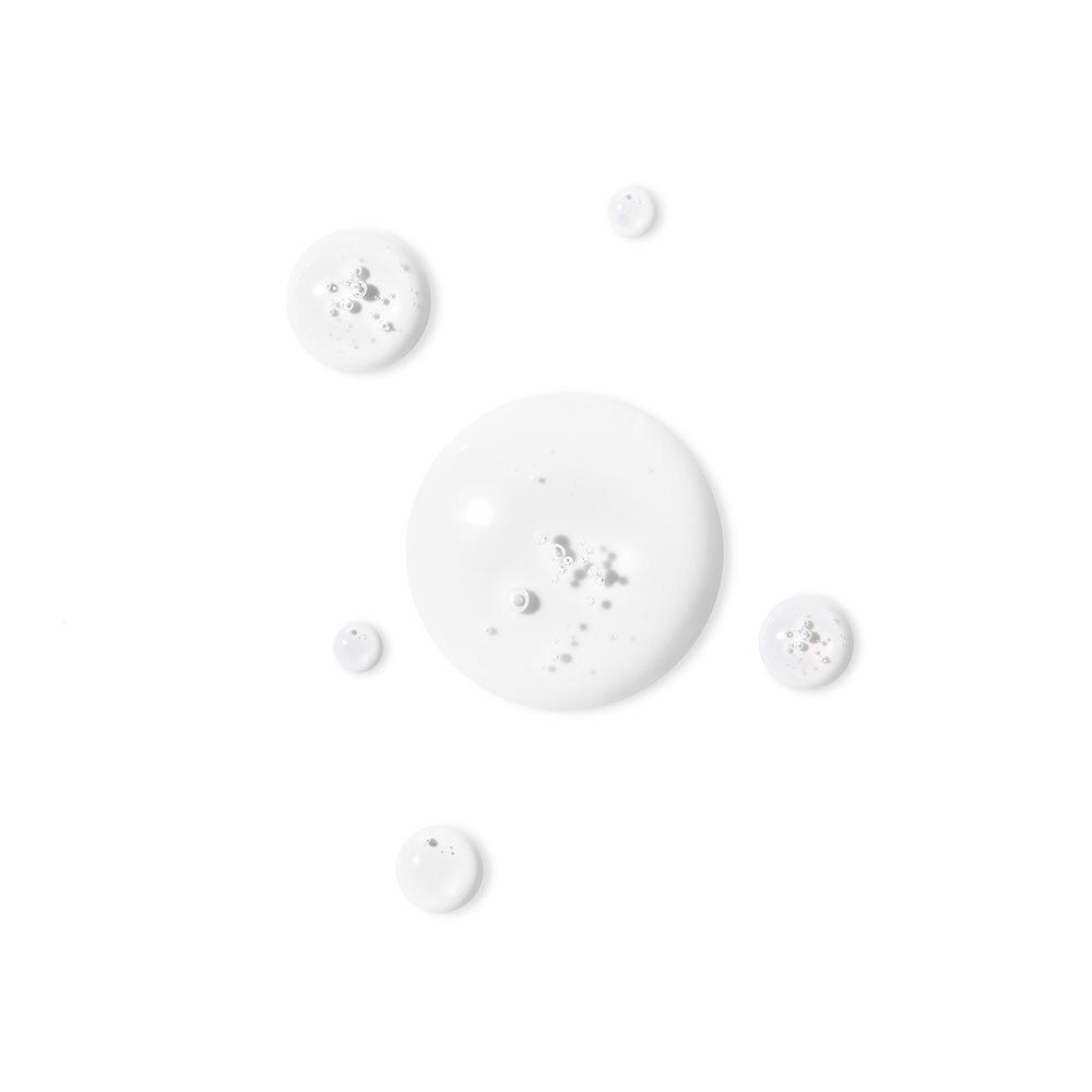 Plusieurs gouttes d'un liquide blanc sur fond blanc.