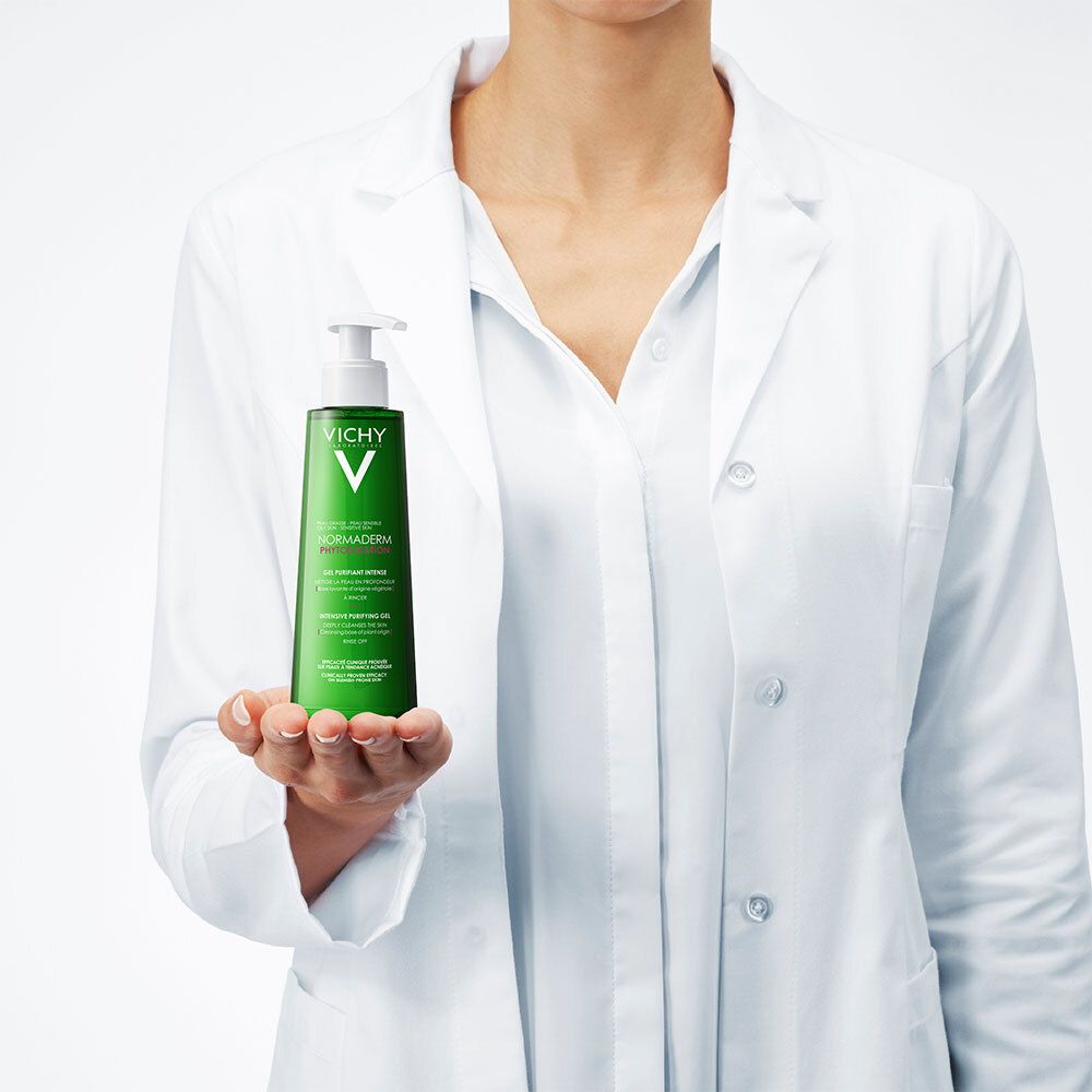 Person in weißem Kittel hält grüne Flasche mit weißem Pumpkopf. Produkt: VICHY Normaderm Phytosolution.
