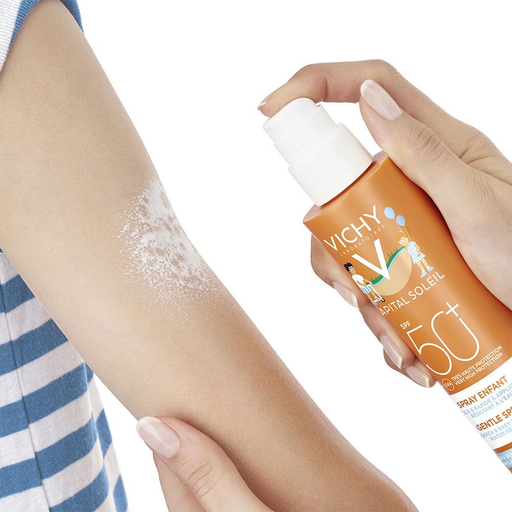 Bras avec écran solaire pulvérisé. Flacon de spray solaire orange avec tête de pulvérisation blanche.