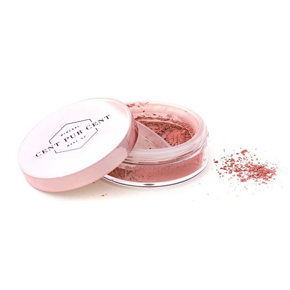 Poudre minérale rose dans un pot transparent avec couvercle rose. Couvercle avec logo. Poudre éparpillée à côté.
