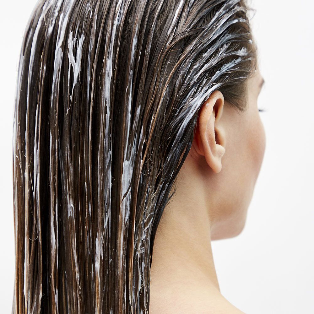 Haar bedekt met witte vloeistof. Achteraanzicht van een persoon.