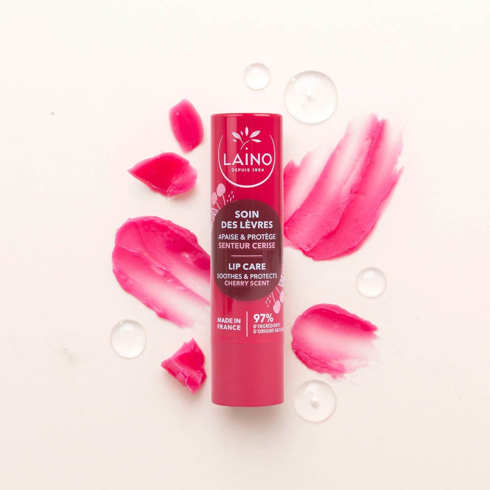 Stick de soin des lèvres rouge avec motifs cerises et éclaboussures roses. Inscriptions: LAINO, SOIN DES LÈVRES, 97% d'ingrédients naturels, LIP CARE.
