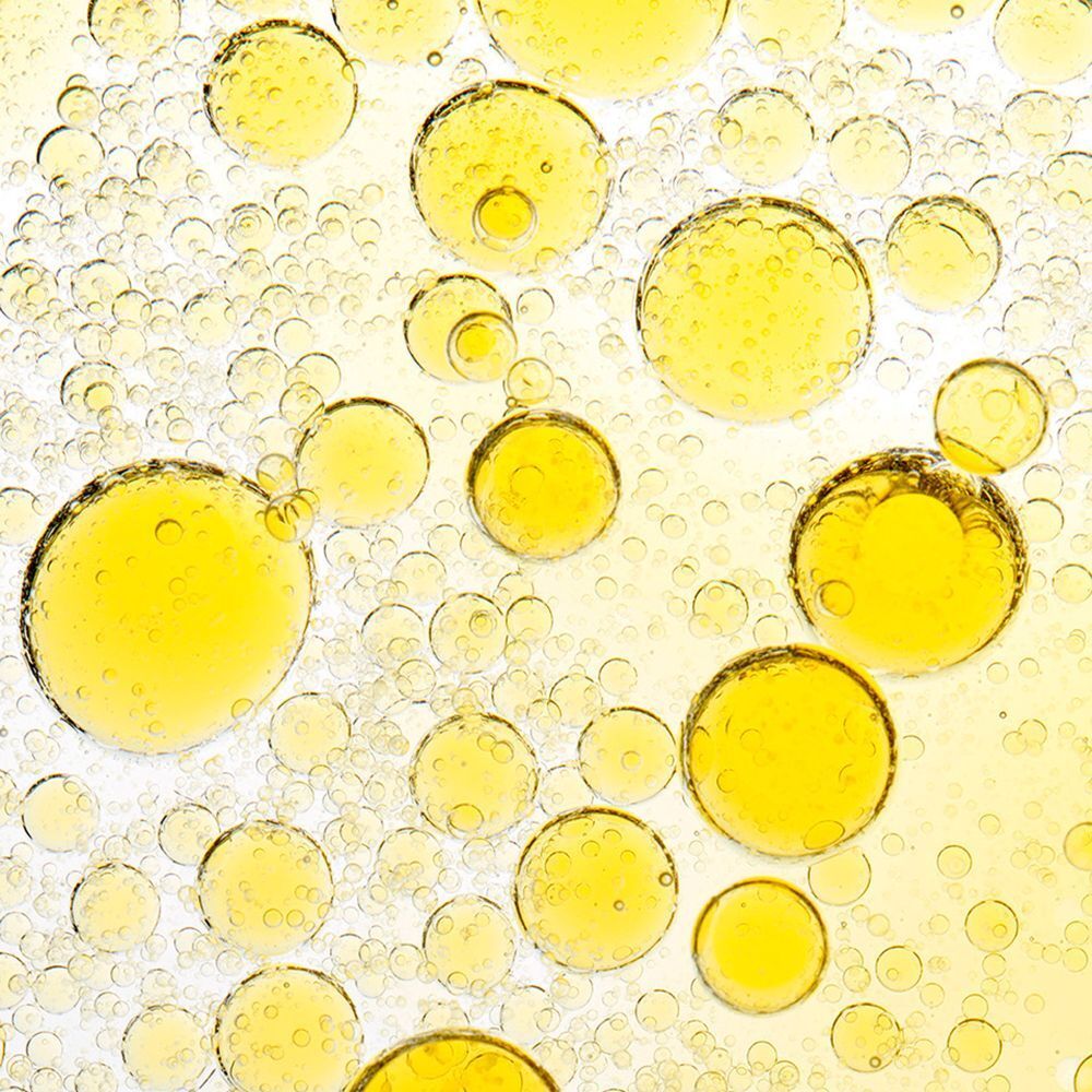 Gros plan de gouttelettes d'huile jaune de différentes tailles. Fond blanc.