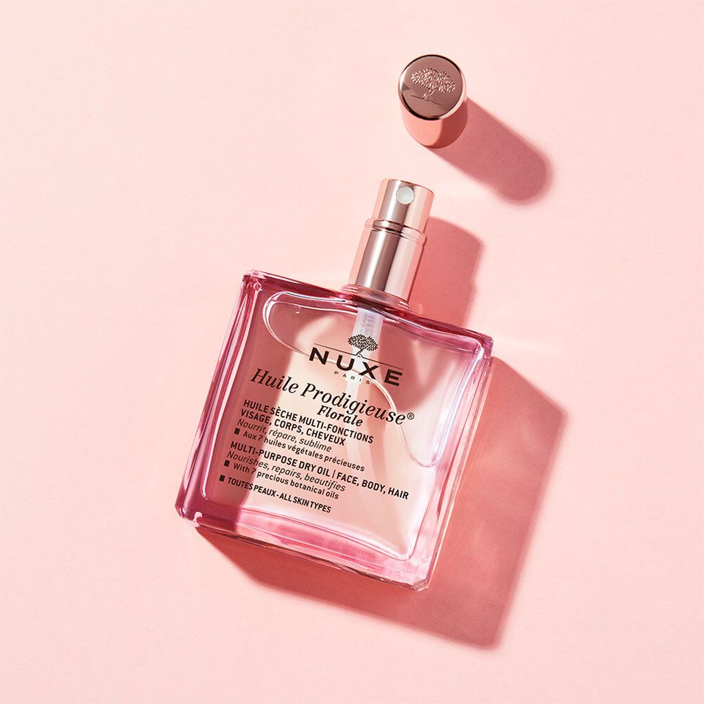 Roze glazen fles met gouden verstuiver en losse dop. Opschrift: Huile Prodigieuse Florale, Nuxe.