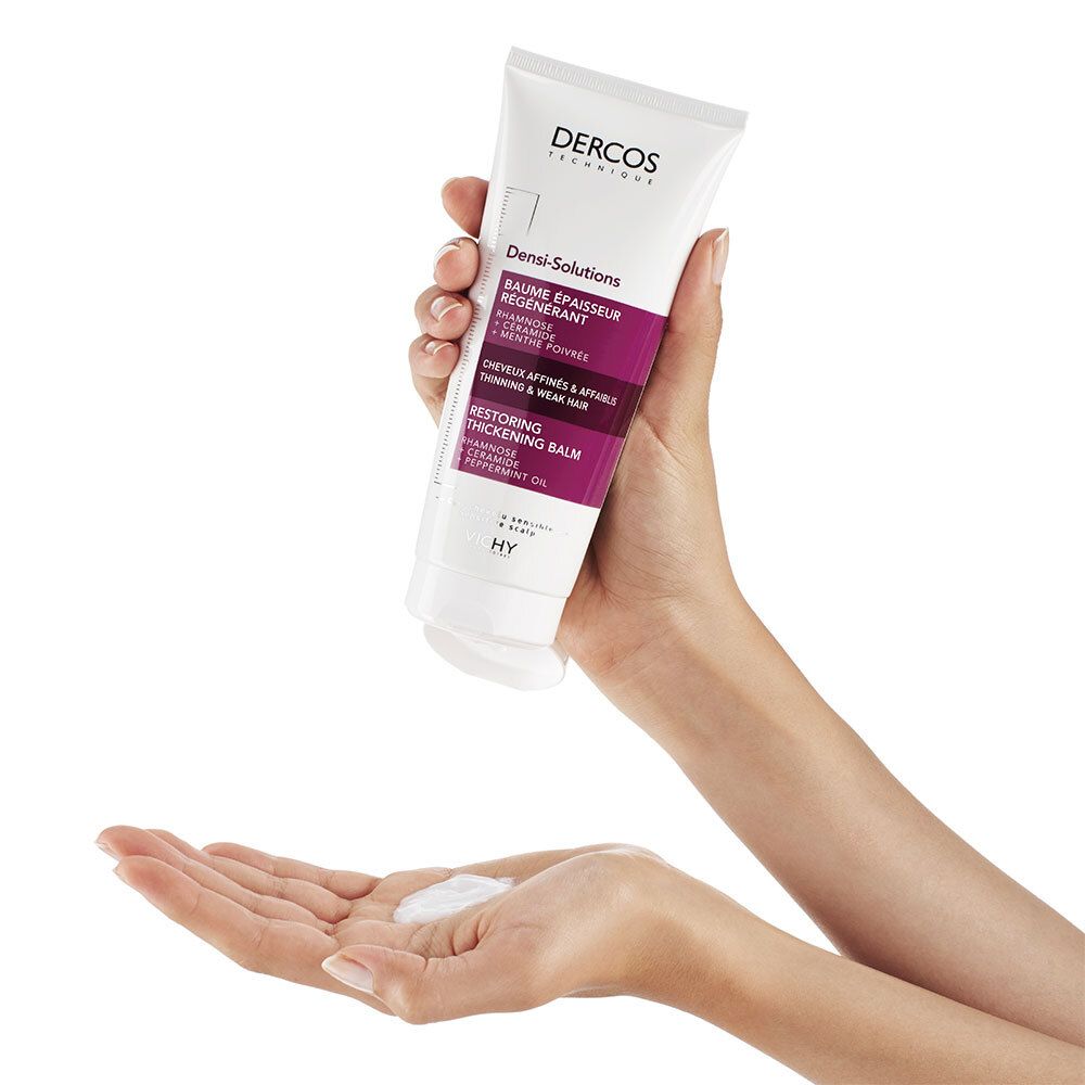 Mains tenant un tube. Produit: Dercos Densi-Solutions. Une main tient le tube, l'autre reçoit une petite quantité de produit.