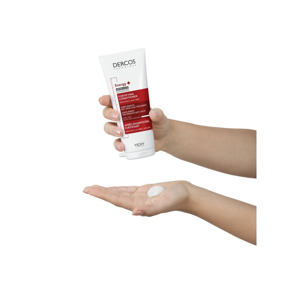 Main tenant un tube. Produit pressé dans la paume. Dercos, Energy+ Amino Acid. Fortifying Conditioner.