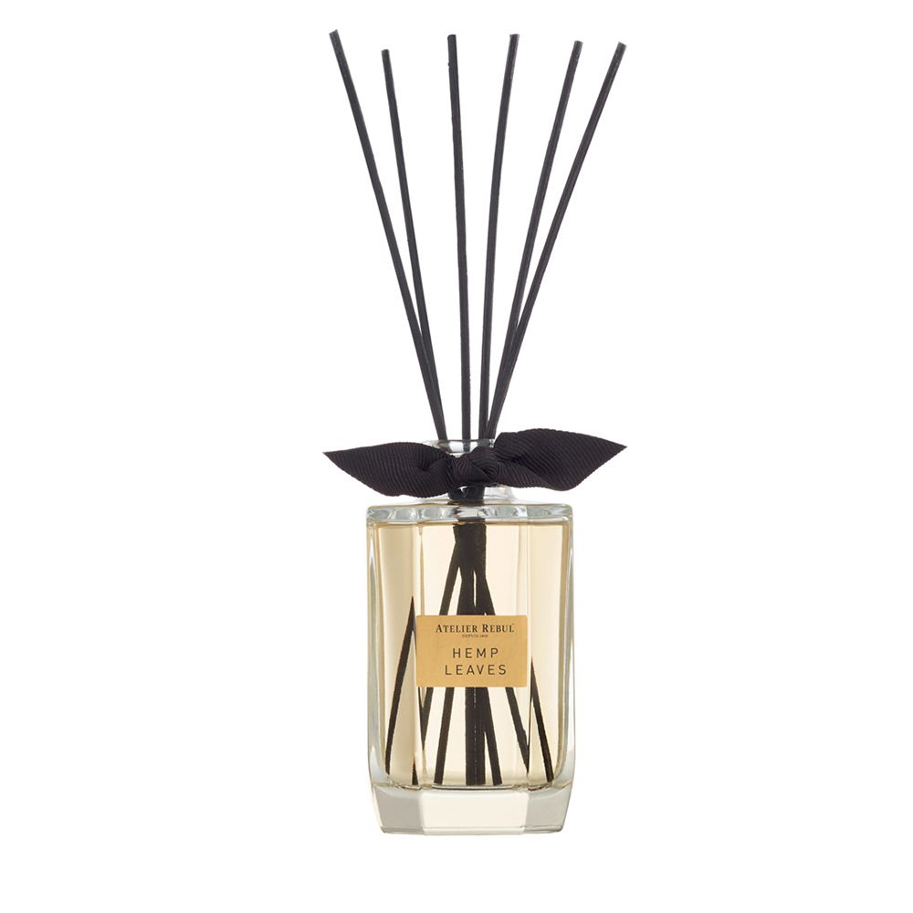ATELIER REBUL® Reed Diffusor. Glasflakon mit schwarzen Stäbchen und Schleife. Produktetikett mit Text.